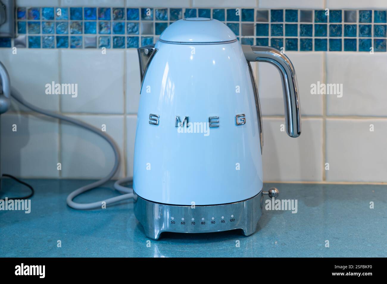 Bollitore blu retrò in stile anni '50 di Smeg - un produttore di elettrodomestici di lusso di marca italiana - in una cucina inglese con pareti piastrellate. REGNO UNITO Foto Stock