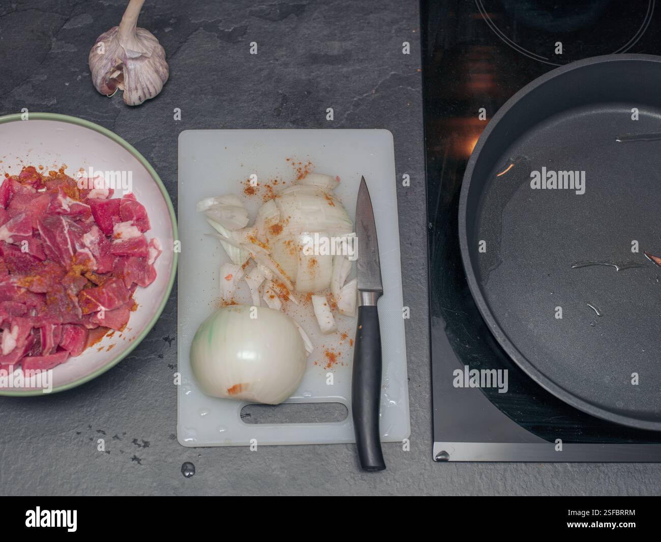 colpo sospeso di un forno elettrico e vitello senza grasso con cipolla sulla scrivania della cucina Foto Stock