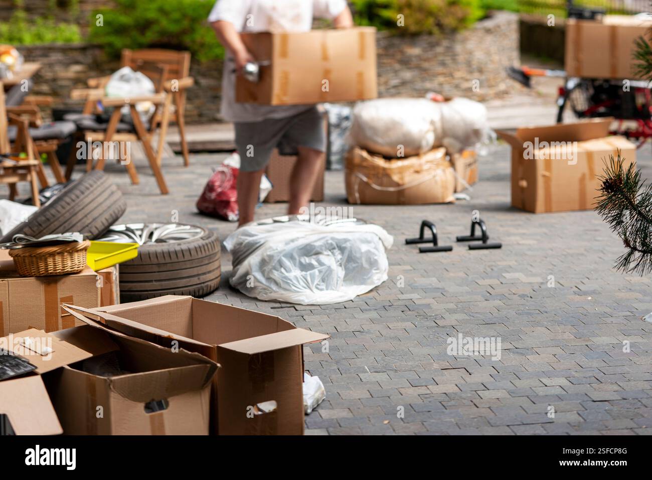 inclinare lo scatto di oggetti domestici sul pavimento e un uomo che trasporta una scatola Foto Stock