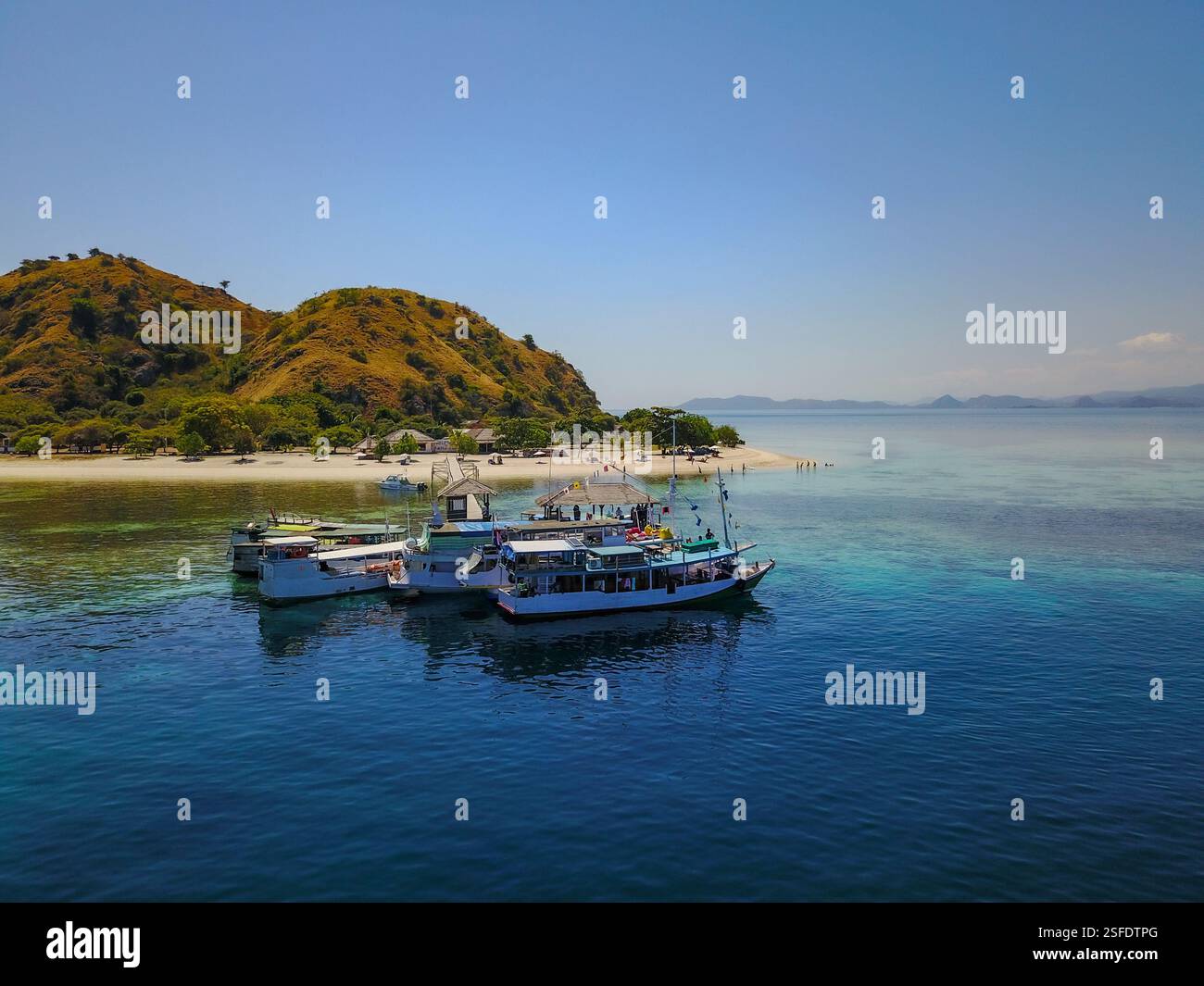Barche turistiche ormeggiate al largo della costa dell'isola di Kelor, del Parco Nazionale di Komodo, di Nusa Tenggara orientale, Indonesia Foto Stock