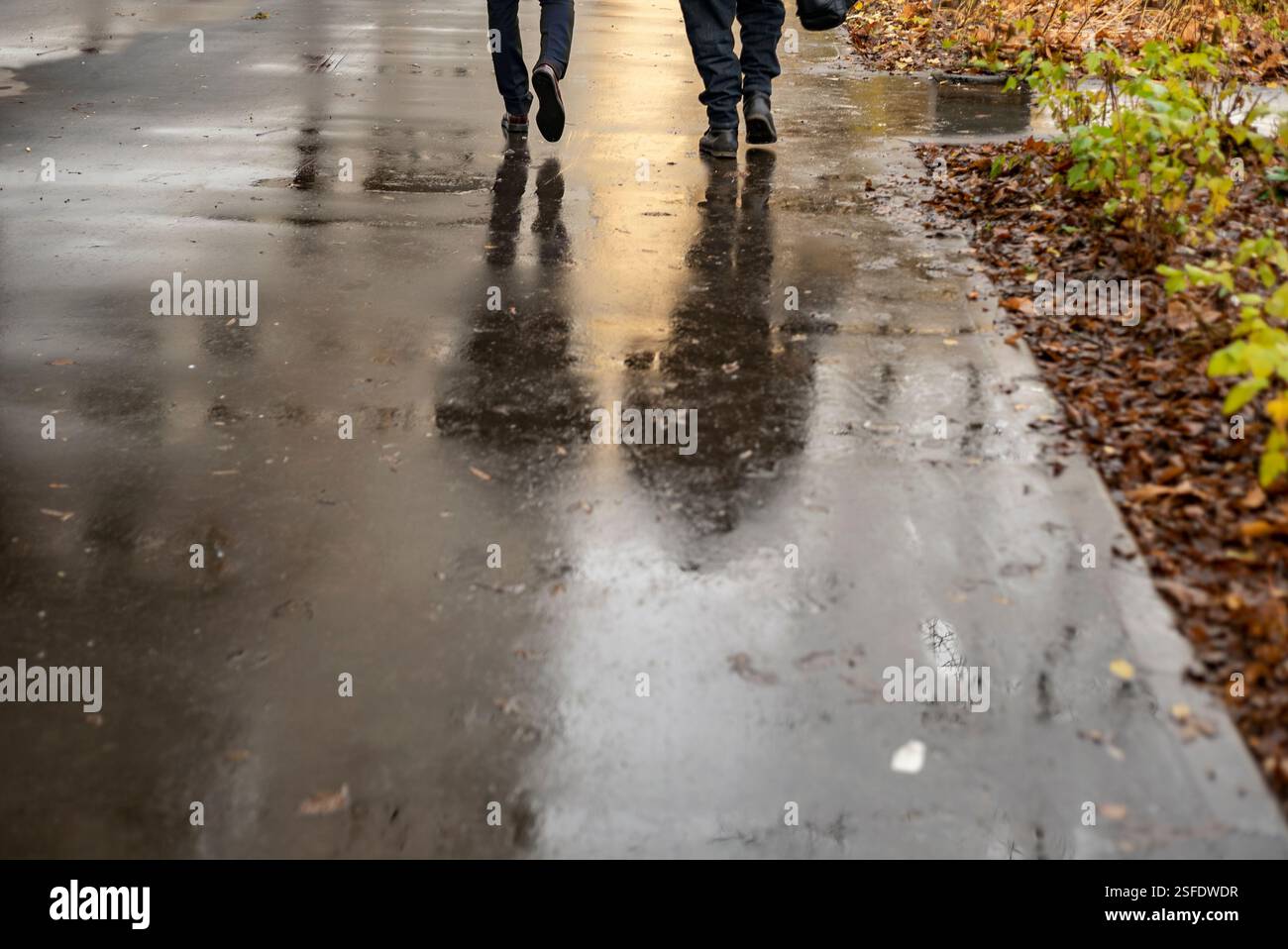 due uomini che camminano sul pedone bagnato, foto diurna di pioggia autunnale Foto Stock