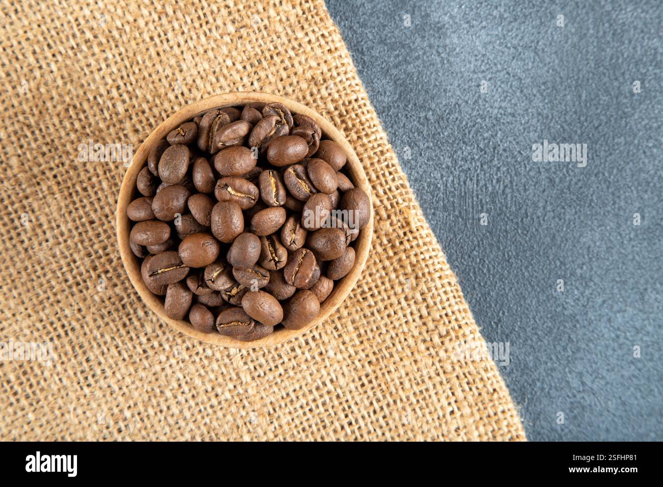 Chicchi di caffè tostati in una ciotola su un sacco di caffè. Foto Stock
