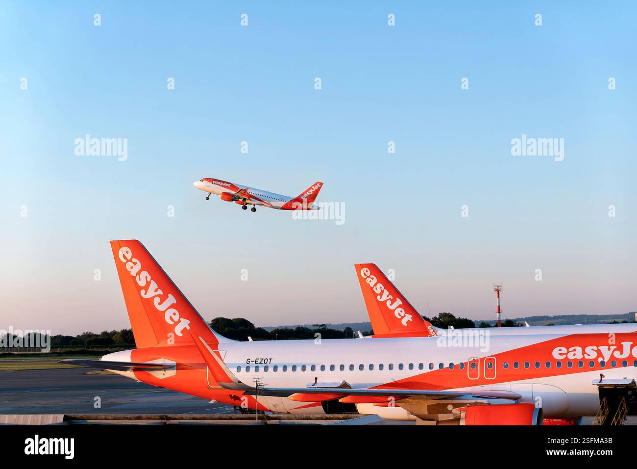 Aeroporto di Bristol Regno Unito. Un aereo easyjet che decolla la mattina presto. Gli aerei easyJet vengono visualizzati parcheggiati sulla pista Foto Stock