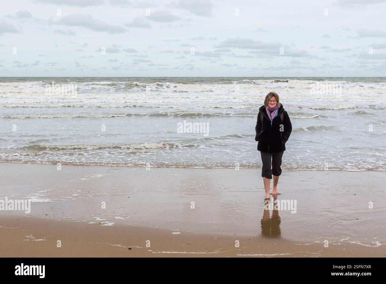 Ostenda, Fiandre occidentali Belgio 10 26 2019 donna attraente che cammina in mare con i pantaloni arrotolati in ginocchio. modello rilasciato Foto Stock