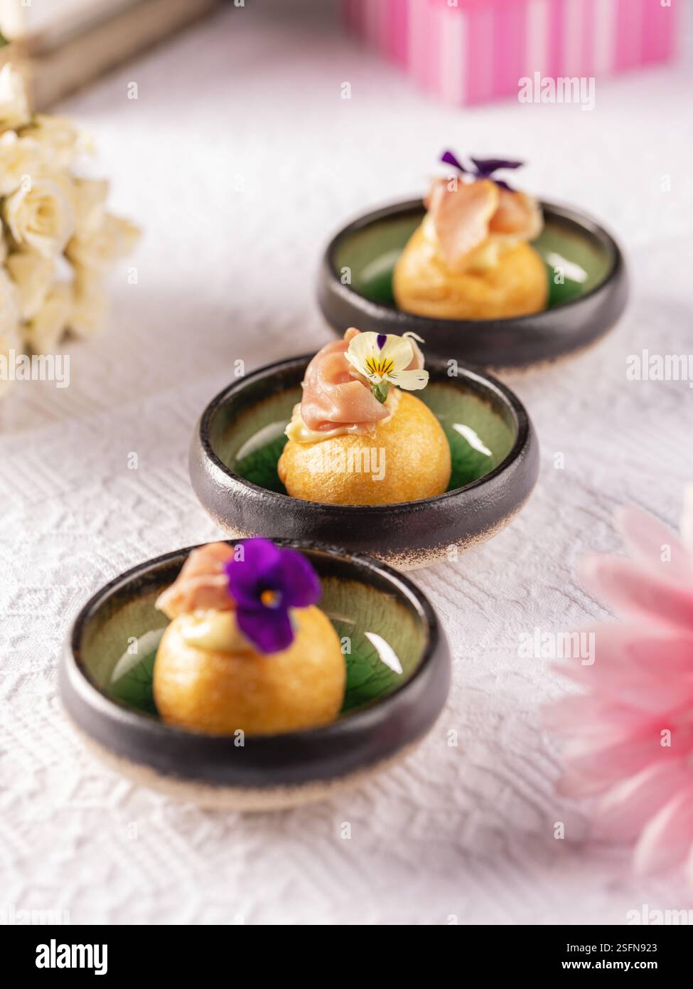 Piccole polpette di formaggio condite con prosciutto di parma e fiori commestibili, per creare un antipasto elegante e delizioso per le occasioni speciali Foto Stock
