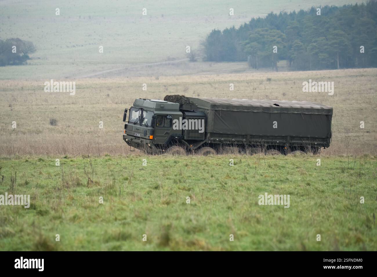 UOMO dell'esercito britannico SV 8x8 EPLS camion logistico che guida una strada non fatta, soldato di fanteria in un esercizio di TAB in primo piano Foto Stock