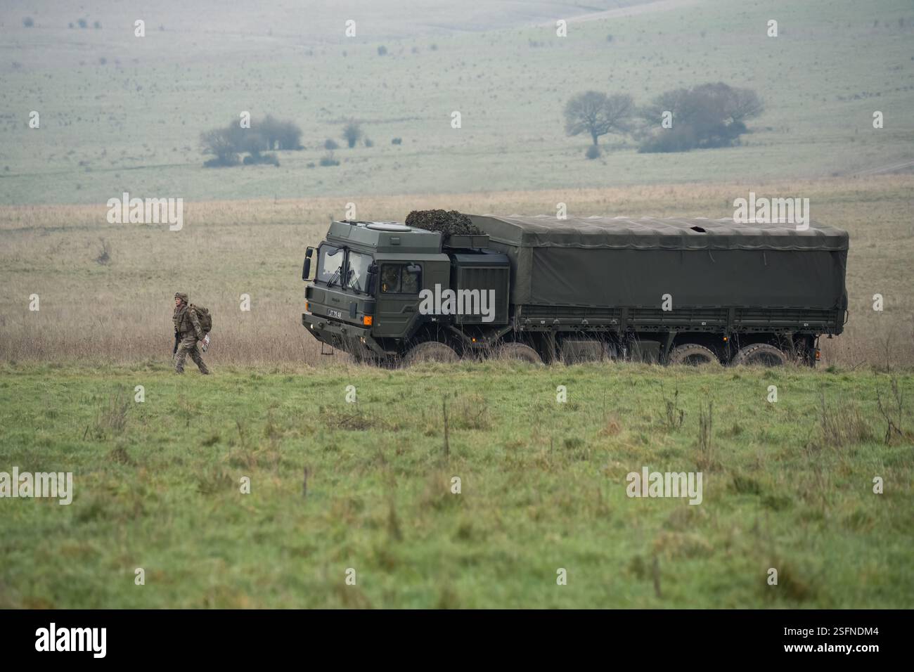 UOMO dell'esercito britannico SV 8x8 EPLS camion logistico che guida una strada non fatta, soldato di fanteria in un esercizio di TAB in primo piano Foto Stock