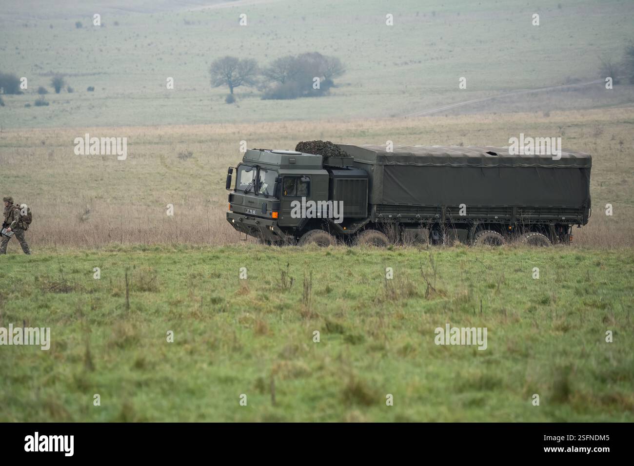 UOMO dell'esercito britannico SV 8x8 EPLS camion logistico che guida una strada non fatta, soldato di fanteria in un esercizio di TAB in primo piano Foto Stock