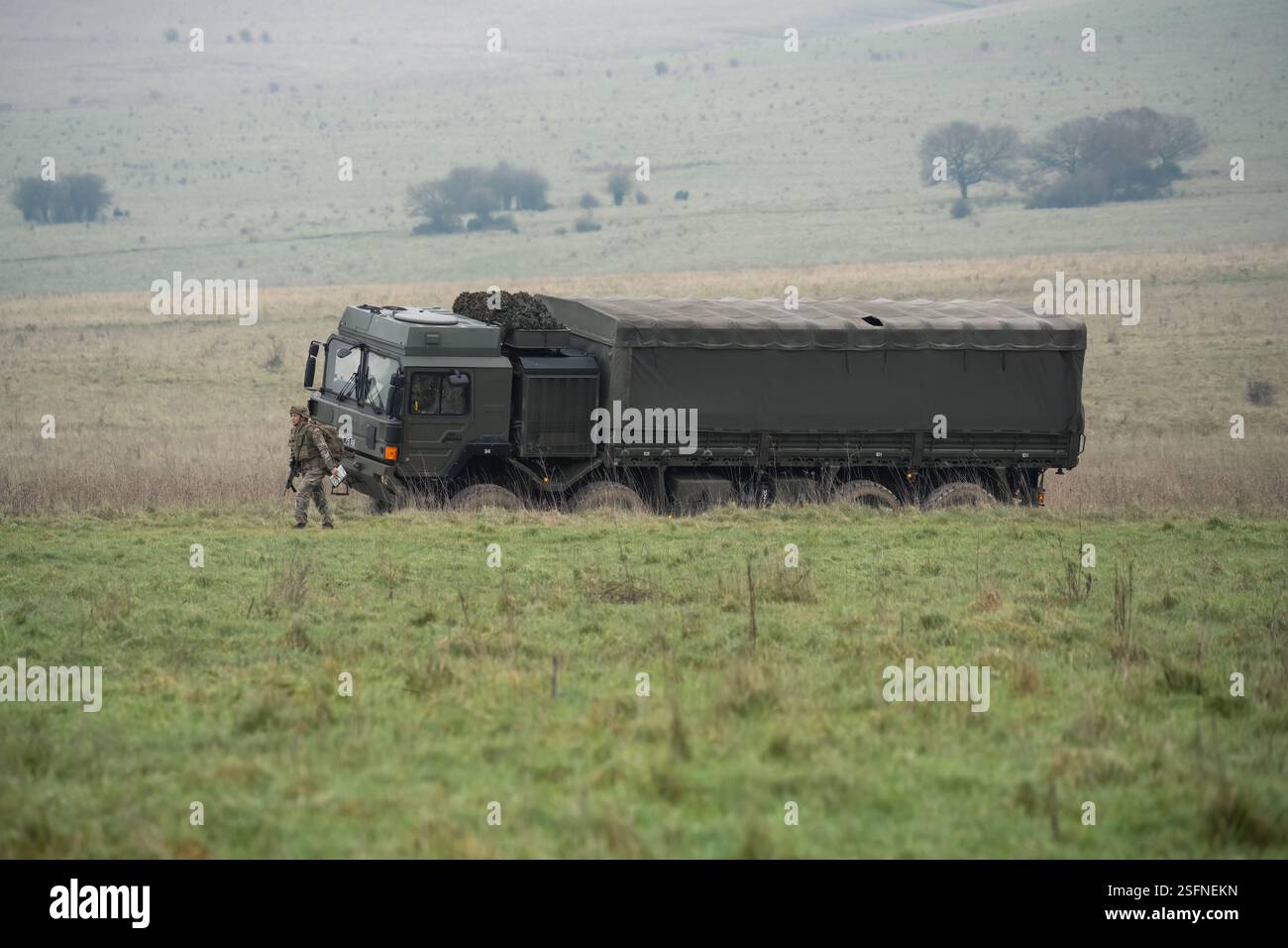 UOMO dell'esercito britannico SV 8x8 EPLS camion logistico che guida una strada non fatta, soldato di fanteria in un esercizio di TAB in primo piano Foto Stock