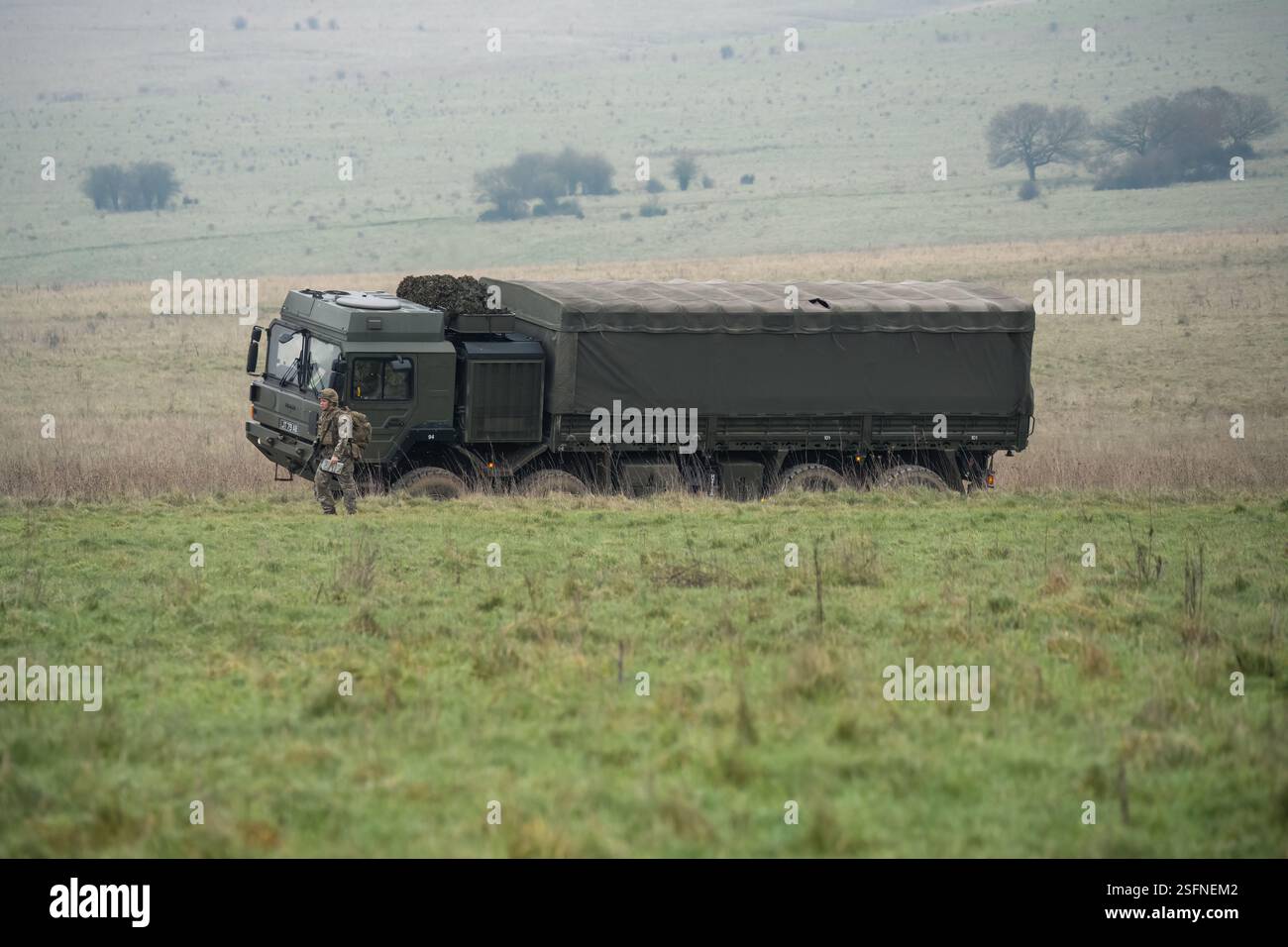 UOMO dell'esercito britannico SV 8x8 EPLS camion logistico che guida una strada non fatta, soldato di fanteria in un esercizio di TAB in primo piano Foto Stock