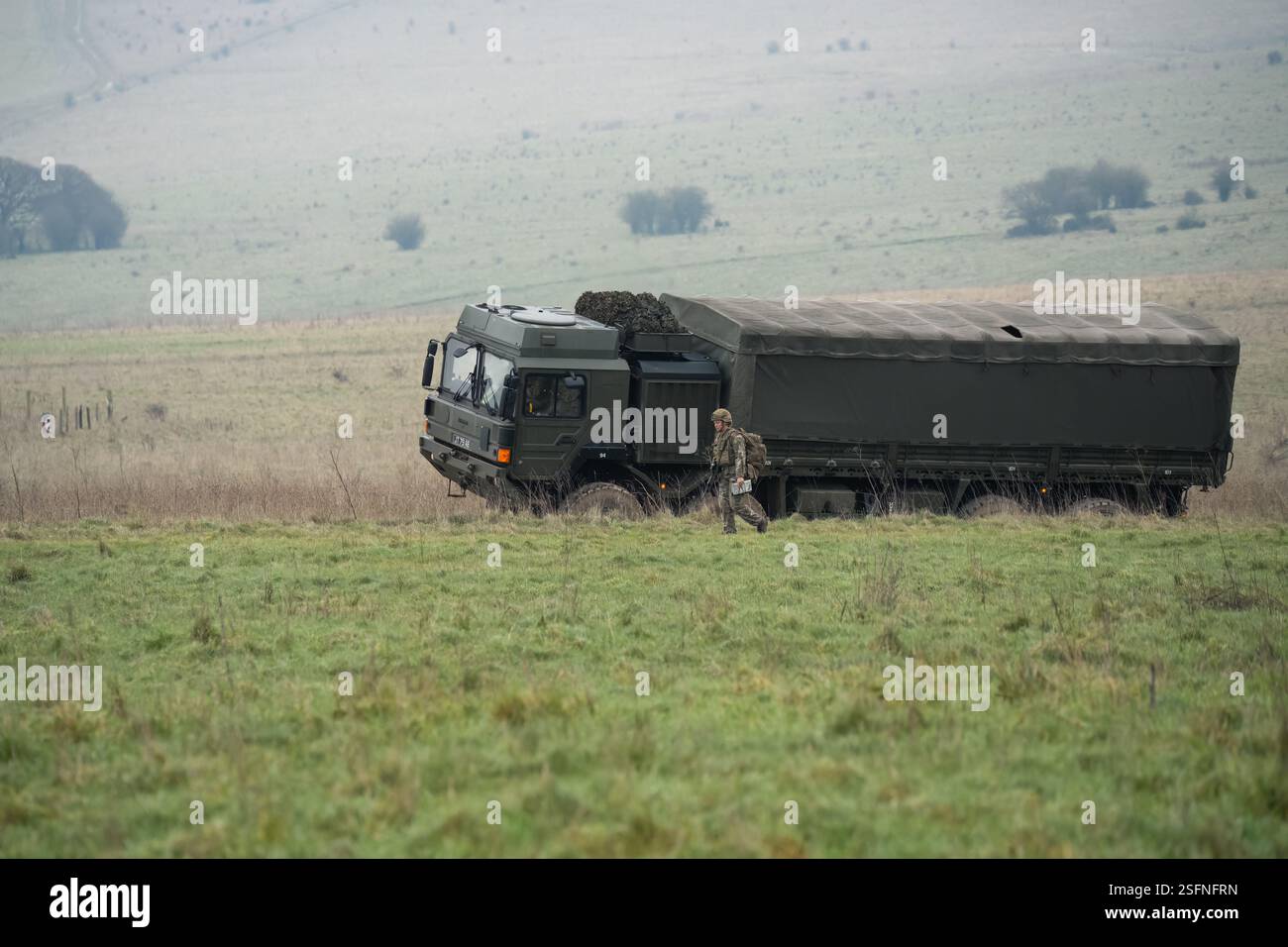 UOMO dell'esercito britannico SV 8x8 EPLS camion logistico che guida una strada non fatta, soldato di fanteria in un esercizio di TAB in primo piano Foto Stock