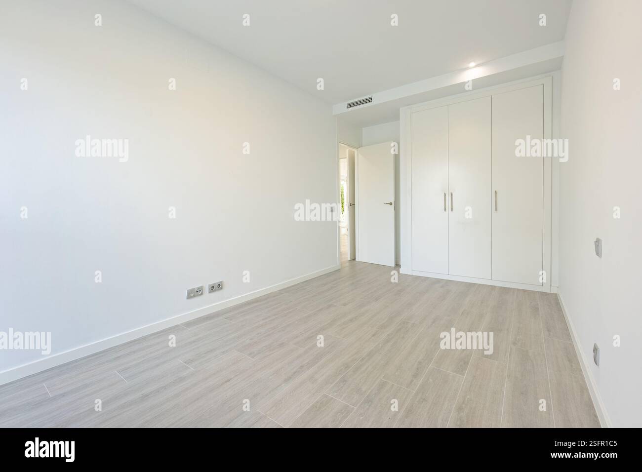 Un'immagine di una camera da letto vuota con pareti bianche e armadi attrezzati in un'agenzia immobiliare per vacanze in stile mediterraneo Foto Stock
