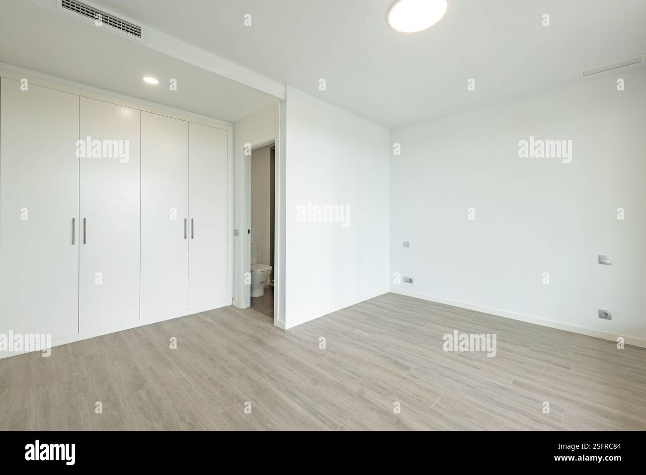 un'immagine di una camera da letto vuota con armadi a muro e un bagno privato in un'agenzia immobiliare per vacanze in stile mediterraneo Foto Stock