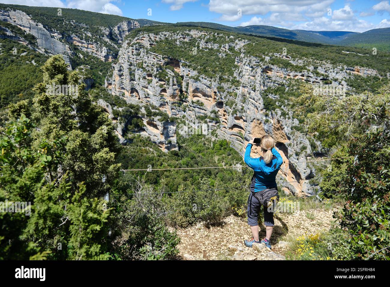 Donna che fotografa un canyon nella Sierra de Guara da un punto panoramico. Foto Stock