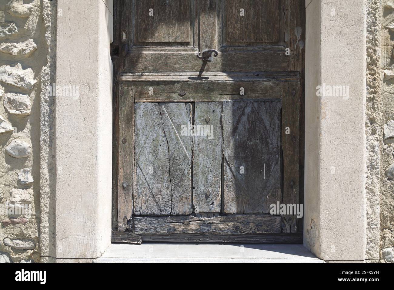 Porta di legno intemprata in una vecchia cornice ad arco in pietra, atmosfera mediterranea, Provenza, Francia, Europa Foto Stock