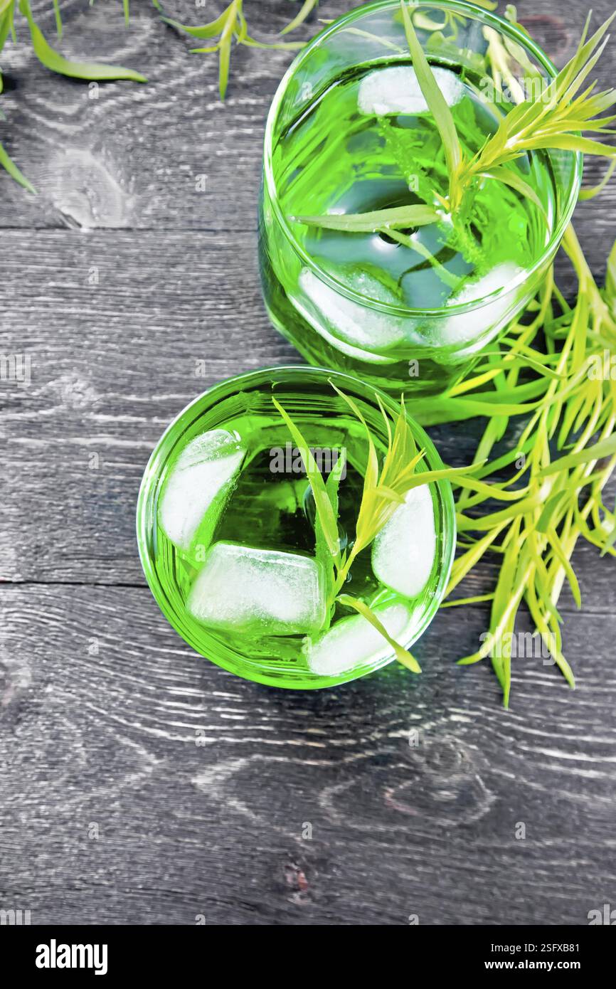 Limonata di dragoncello con ghiaccio in due bicchieri, rametti di estragone su uno sfondo di legno da sopra Foto Stock