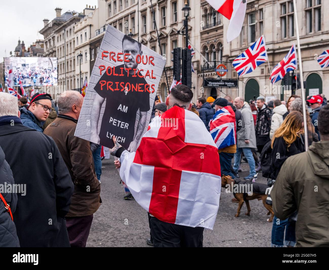 Il manifestante con la bandiera inglese sul retro regge il cartello "Free Tommy Robinson" a Whitehall, Londra. Evento "Stop the Isolation" o "Unite il Regno". Foto Stock