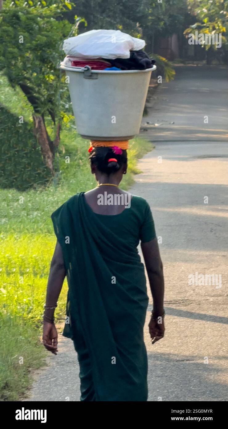 Una cameriera porta il bucato sulla testa al Sarayana Ayurvedic Hospital Coimbatore, India, nel Tamil Nadu Foto Stock