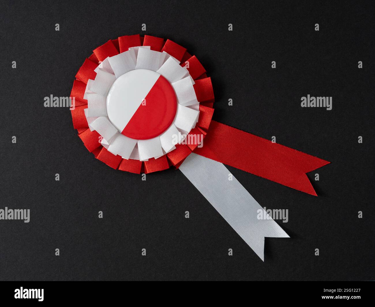 Rosetta a nastro rossa e bianca su sfondo nero, a simboleggiare il successo o l'orgoglio nazionale. Colori nazionali polacchi. Foto Stock