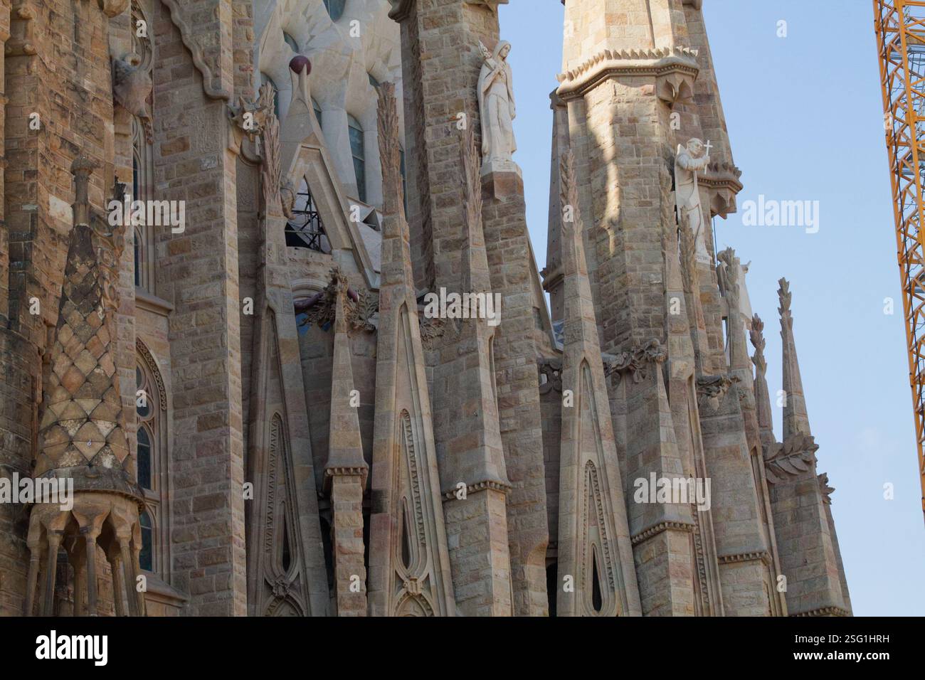 Vista ravvicinata dell'intricata muratura in pietra e delle guglie di una famosa cattedrale, che mostra sculture dettagliate e caratteristiche architettoniche contro una chiara b Foto Stock