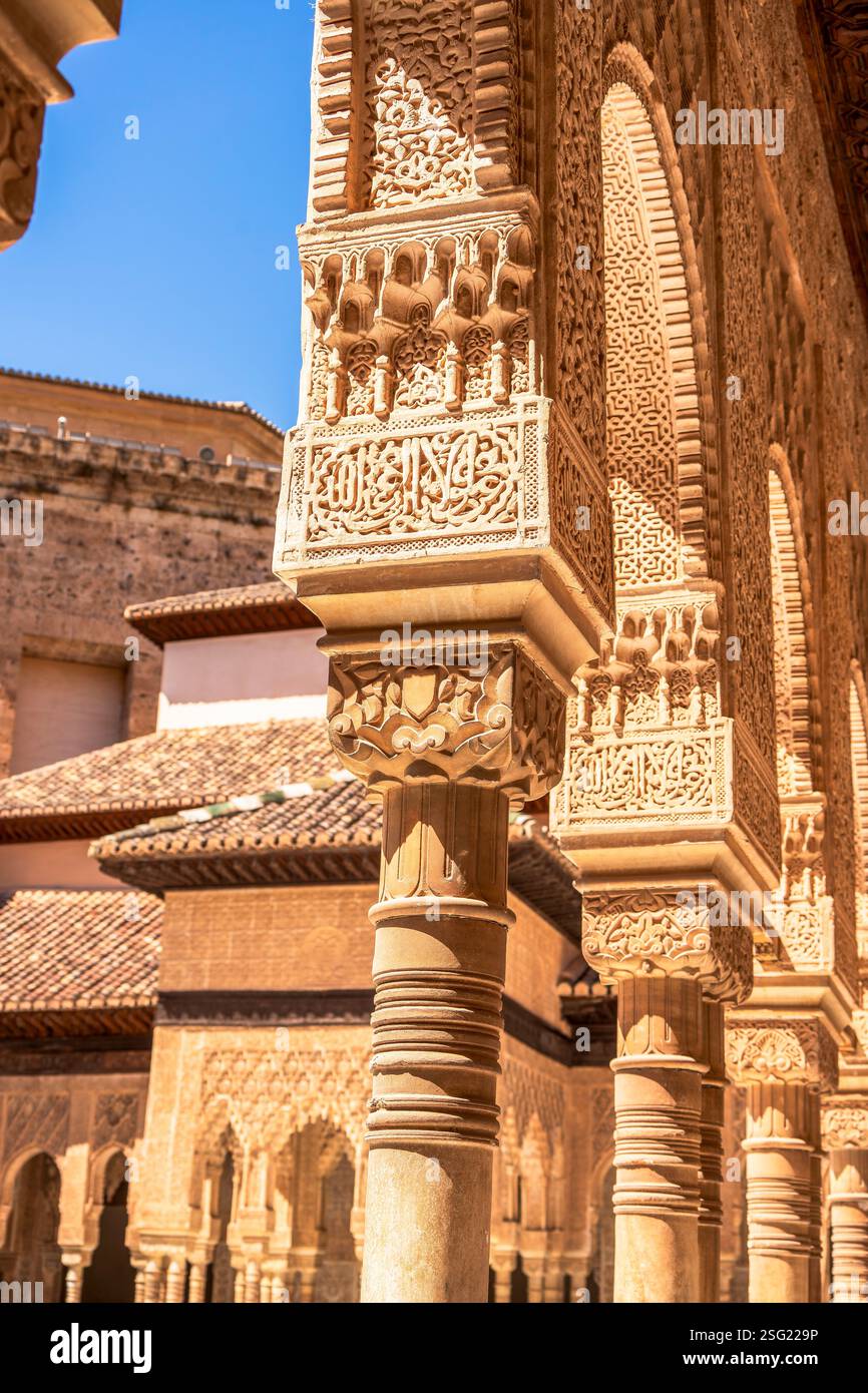Archi Nasridi e colonne scanalate sottili intagliate nella Corte dei Leoni all'Alhambra, che mostrano le capitali dei muqarnas e la calligrafia araba Foto Stock