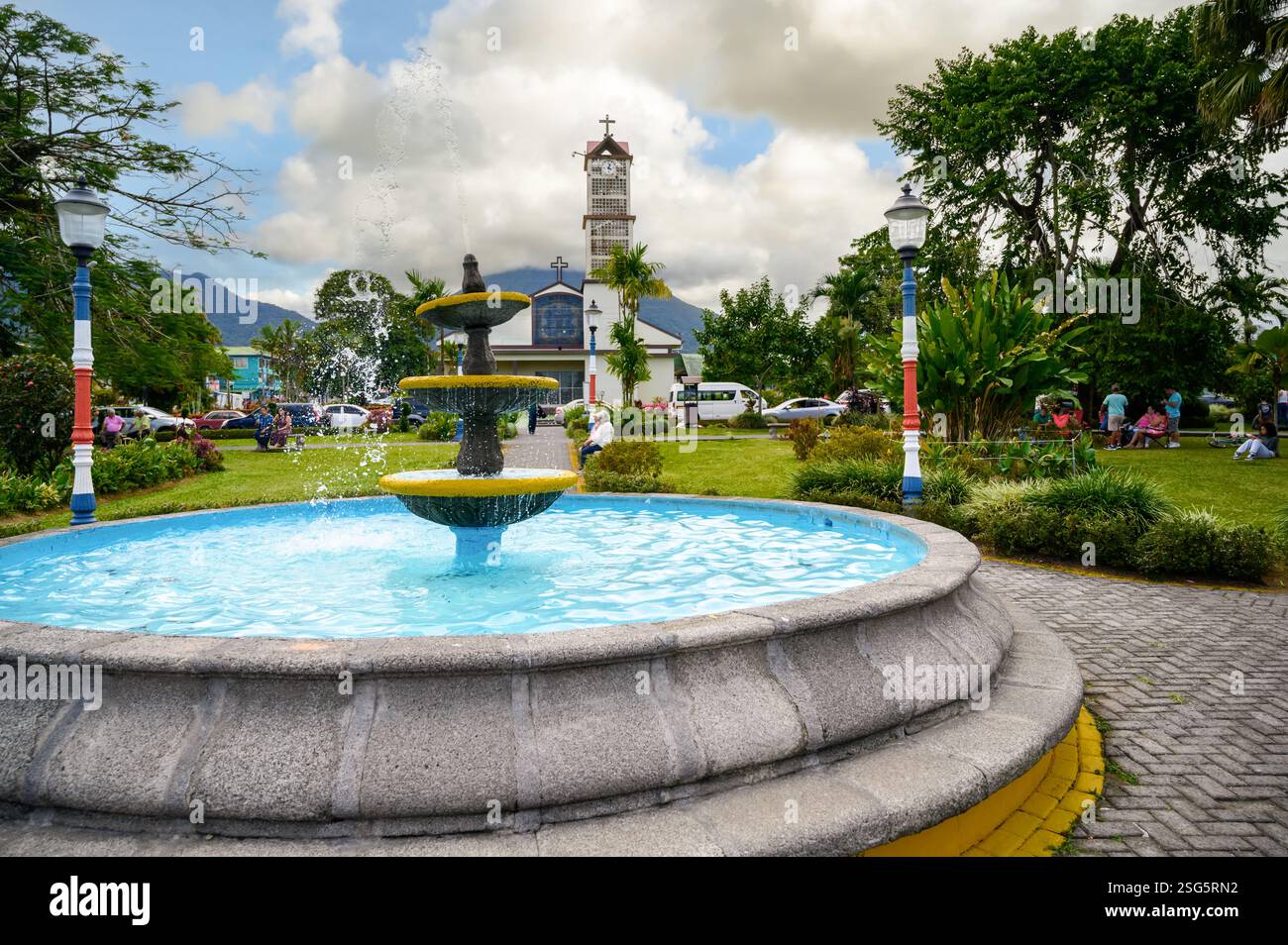 Parco e fontana la fortuna con chiesa Iglesia de la fortuna de San Carlos e vulcano Arenal sullo sfondo, Costa Rica, America centrale. Foto Stock