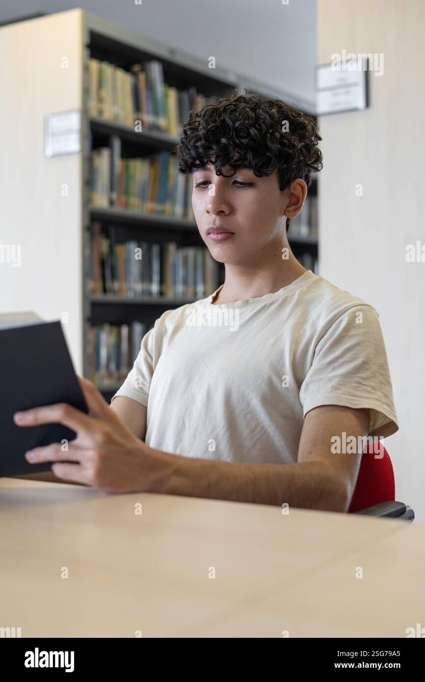 Uno studente dedicato che studia per un esame, concentrato e circondato da materiali di studio. Perfetto per temi di istruzione, preparazione agli esami e accademici Foto Stock