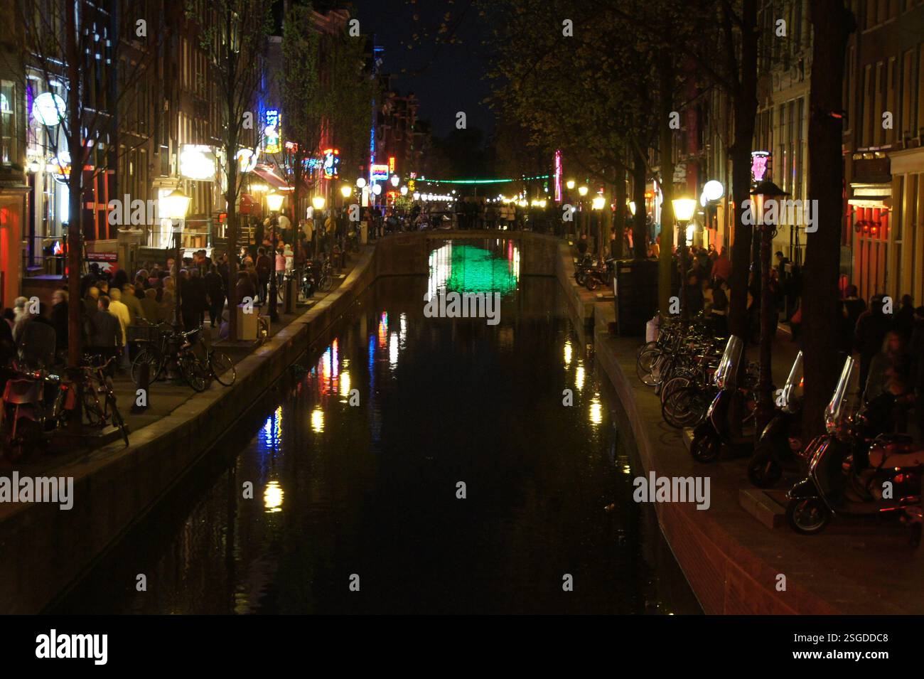 Le luci al neon illuminano il famoso quartiere a luci rosse di Amsterdam, proiettando un vibrante bagliore sulle strade acciottolate. L'atmosfera unica di Amsterdam Foto Stock