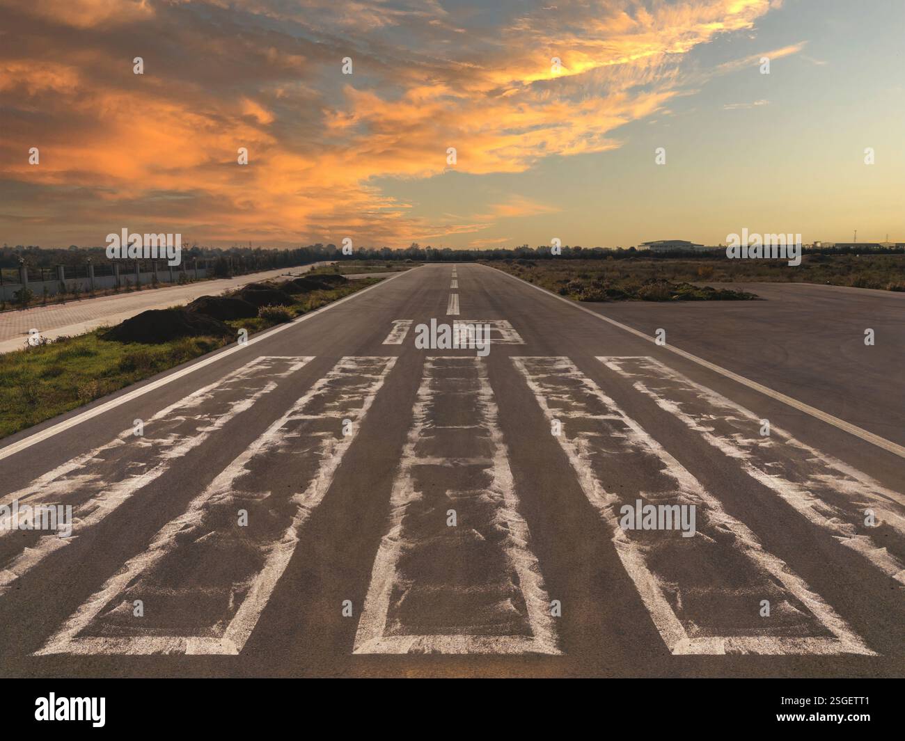 Vista prospettica di una piccola pista di atterraggio in una zona rurale al tramonto, che si restringe dalla testa della pista Foto Stock