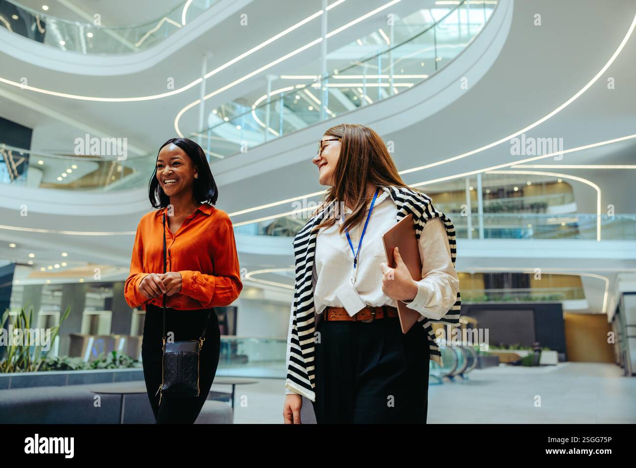 Colleghi dinamici in un ufficio all'avanguardia, impegnati in conversazioni sulla consulenza finanziaria. L'ambiente di lavoro moderno migliora la loro qualità professionale Foto Stock