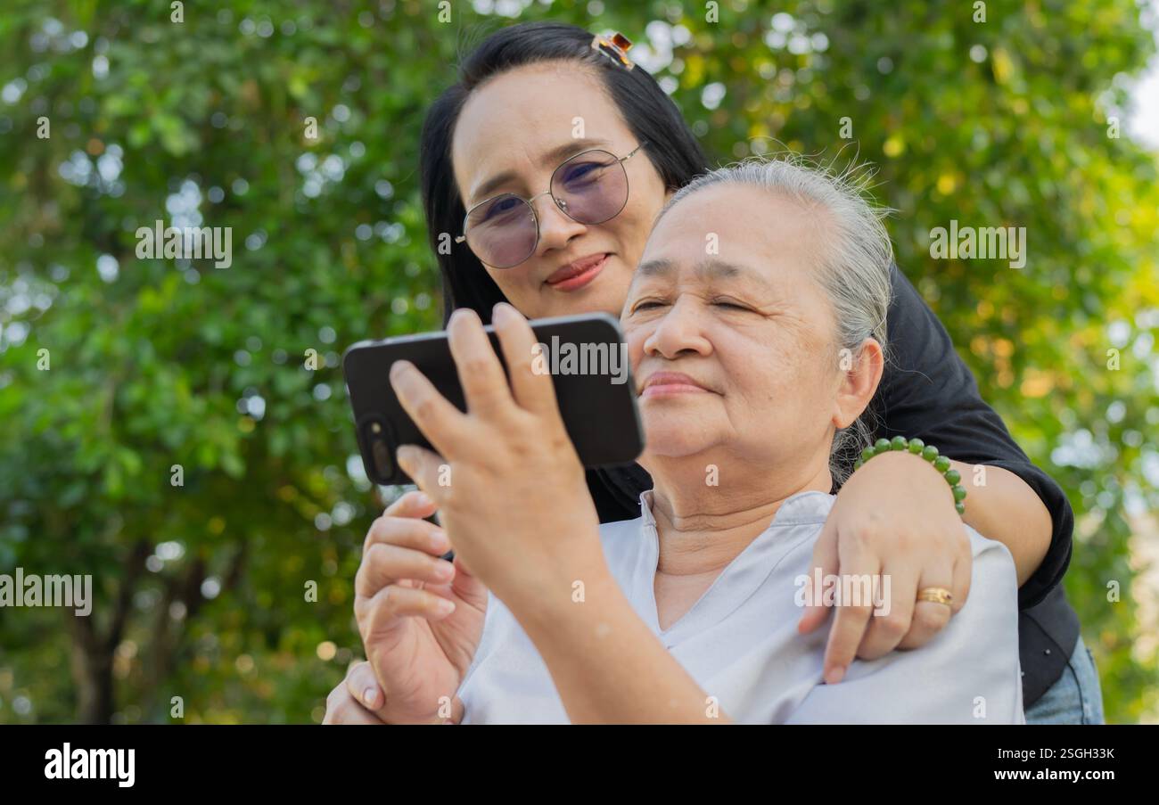 Allegra nonna e nipote che si divertono insieme ai social media sul cellulare del parco. Foto Stock
