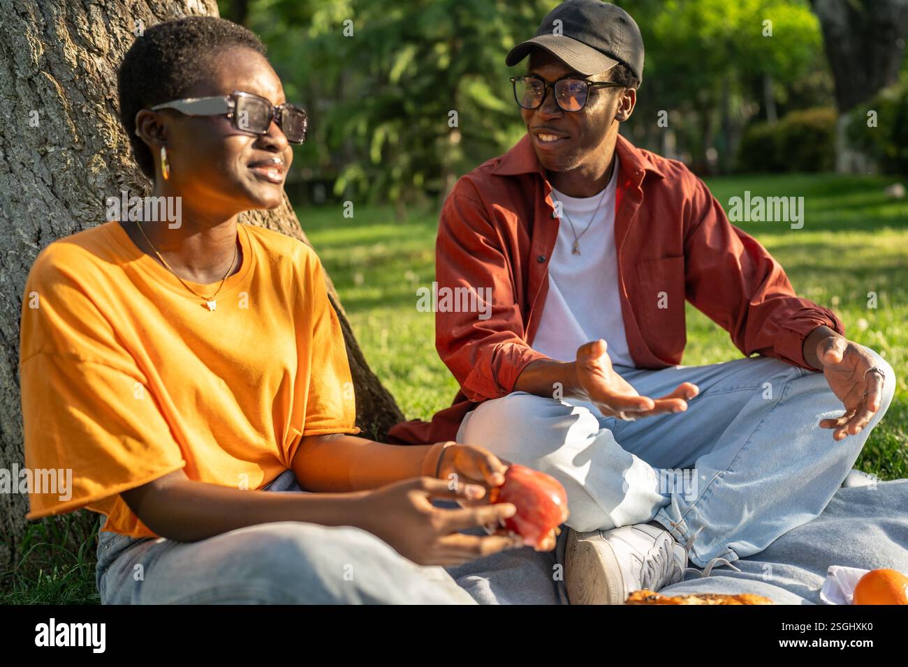 La coppia nera ama fare un picnic tranquillo, sedersi sulla coperta assaporando spuntini durante la conversazione, uscire all'aperto Foto Stock