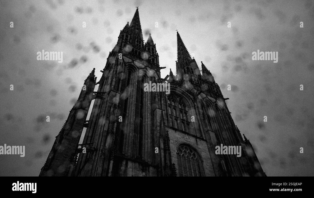 Cattedrale di Quimper con le sue due torri gotiche, sotto la pioggia con gocce di pioggia sulla lente Foto Stock
