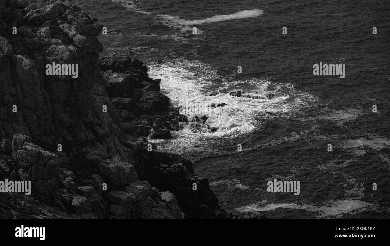 Una scogliera con onde e correnti che si schiantano contro le rocce Foto Stock