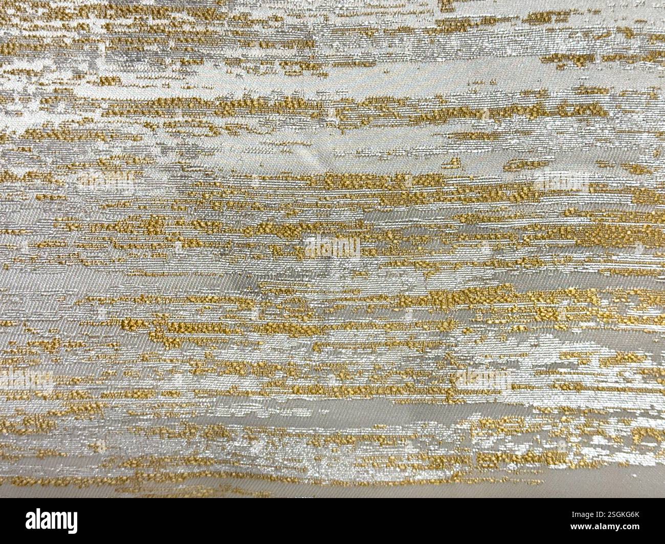 Primo piano di un tessuto decorativo con motivo a nuvole a tinta casuale color oro e grigio. Trama dello sfondo senza cuciture. Foto Stock