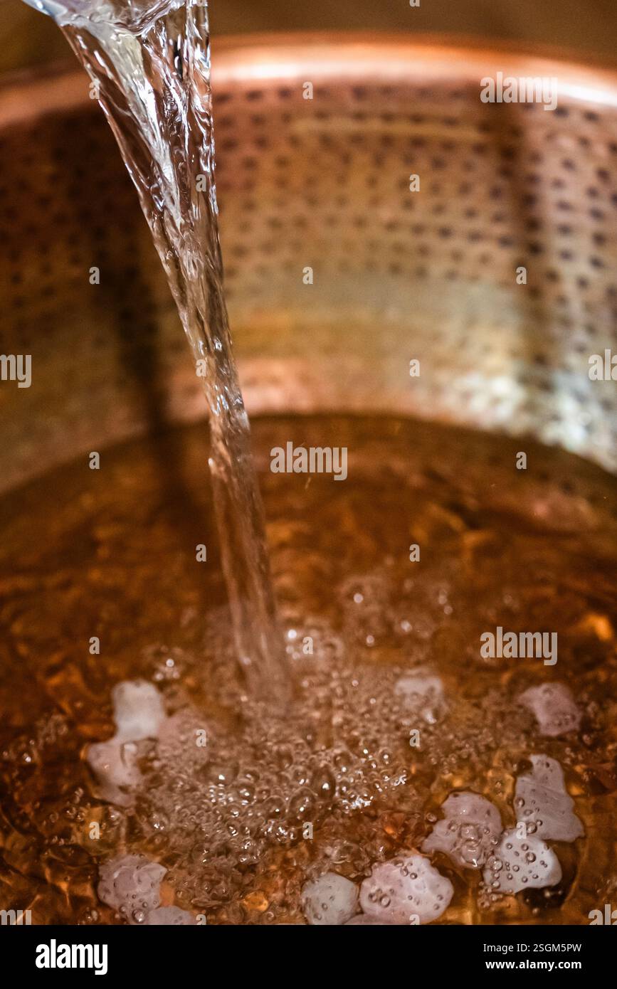 Acqua che si riversa in una vasca di rame per un bagno rilassante. Foto Stock