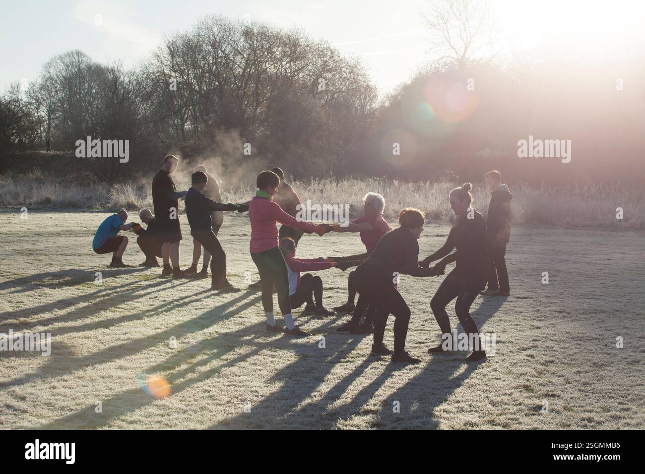 Un gruppo di persone impegnato in attività all'aperto in una mattina gelida, formando un cerchio e tenendosi per mano, sale Water Park, Manchester, Regno Unito Foto Stock