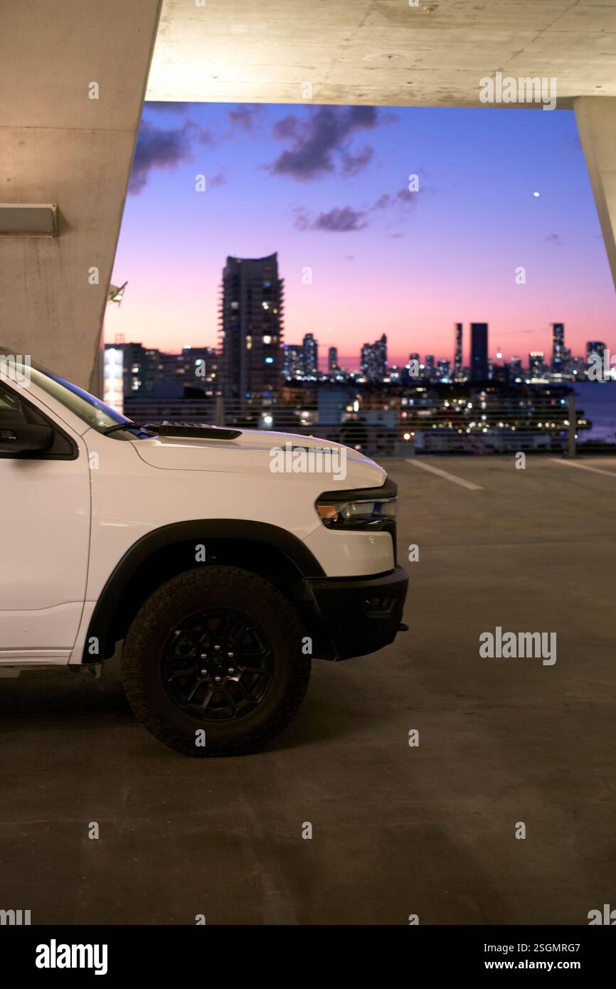 Camion bianco parcheggiato in una struttura in cemento con uno skyline della città al tramonto sullo sfondo, Miami, Florida, Stati Uniti Foto Stock