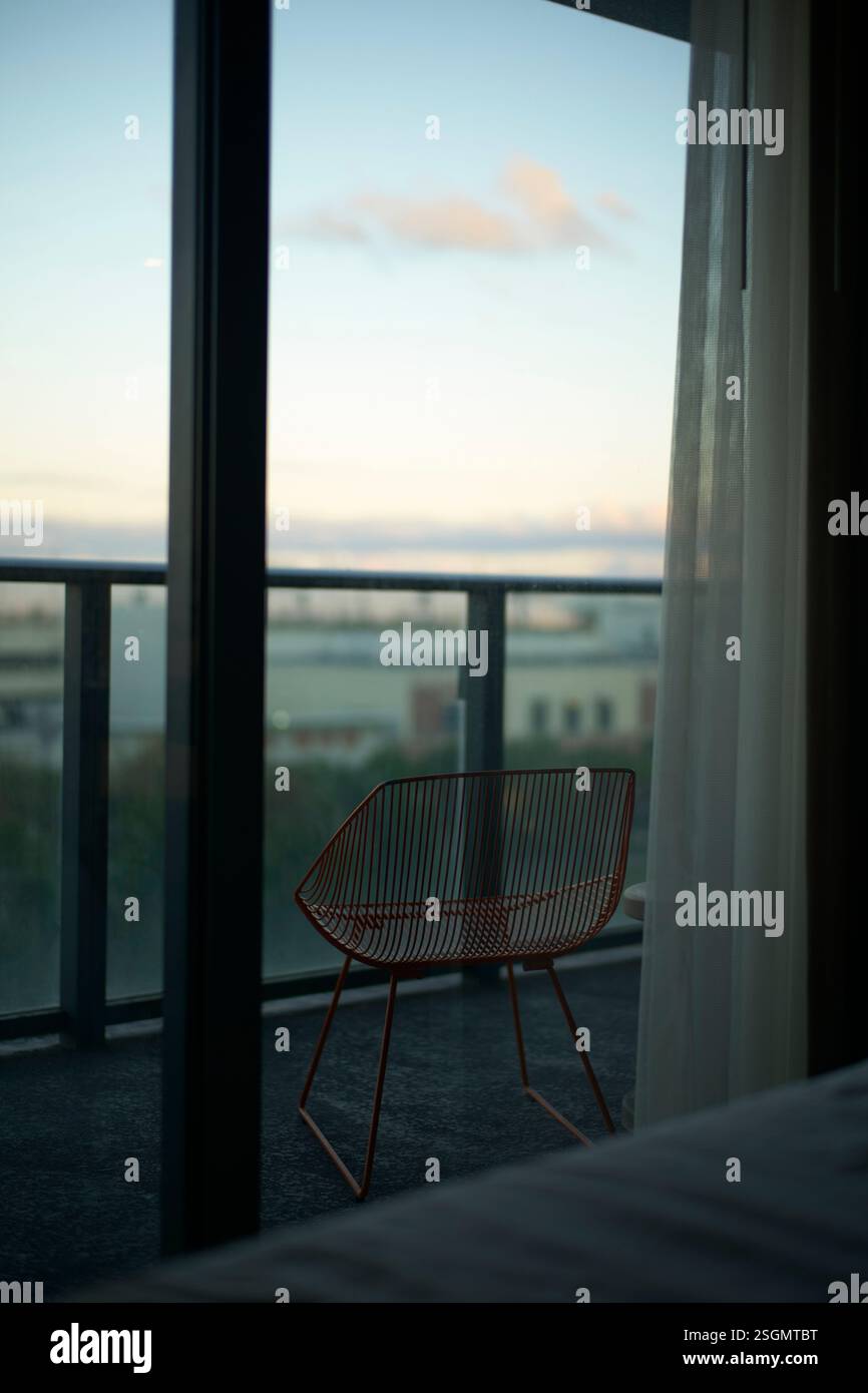 Sedia Orange Wire su un balcone con vista sugli edifici e il cielo limpido al tramonto, Miami, Florida, Stati Uniti Foto Stock