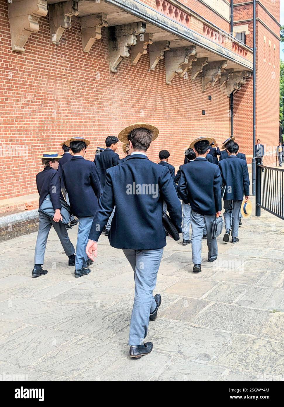 Ragazzi della scuola pubblica in uniforme e cappelli di paglia che camminano per strada Foto Stock