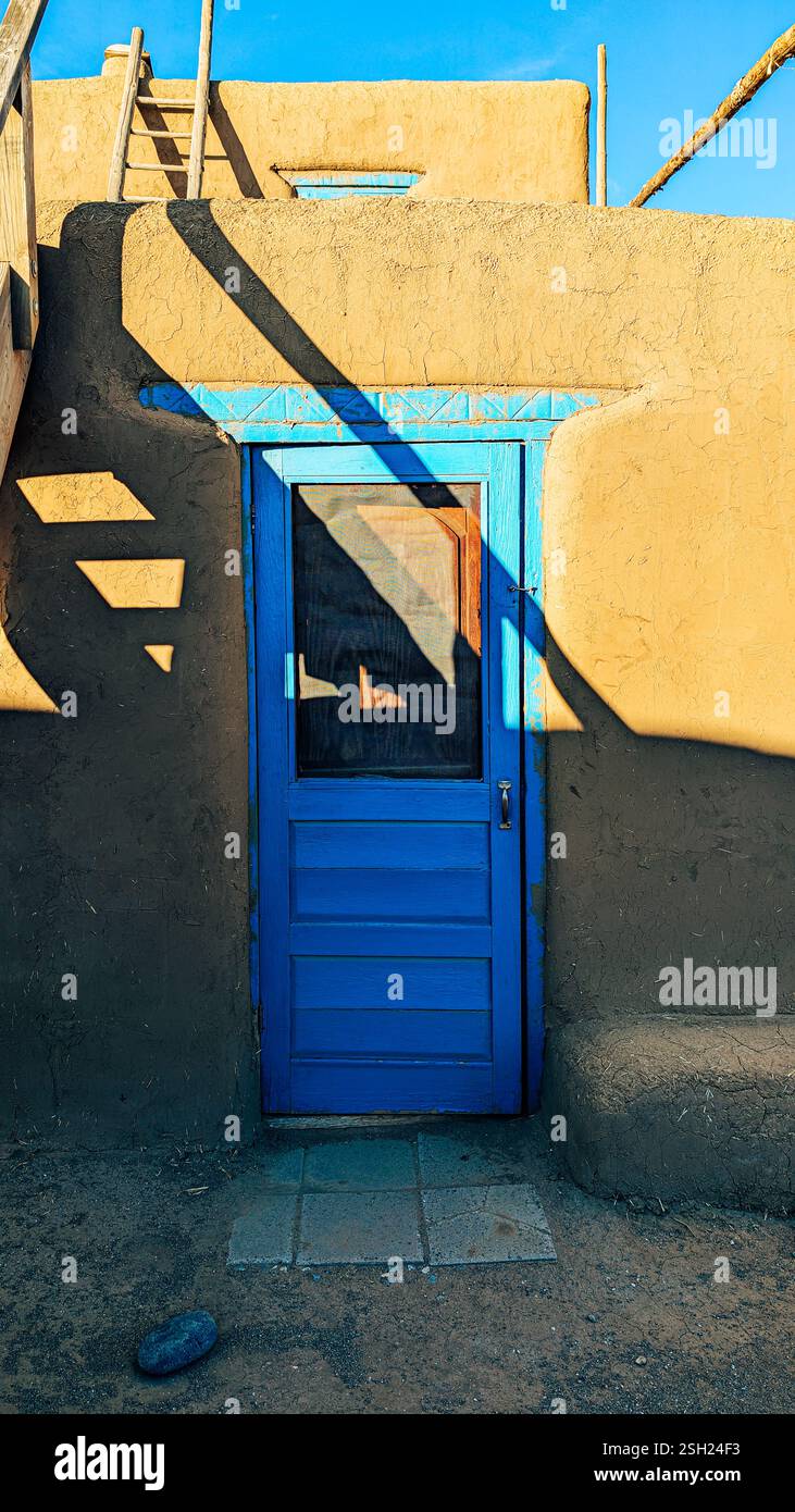 Rustica Adobe Home con vivace porta blu e ombre Foto Stock