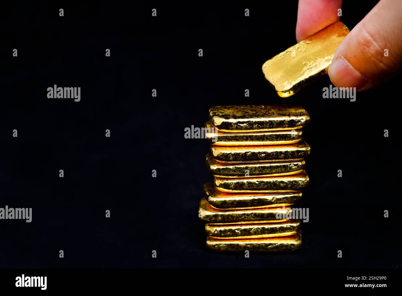 Primo piano della mano con barre dorate su sfondo nero Foto Stock