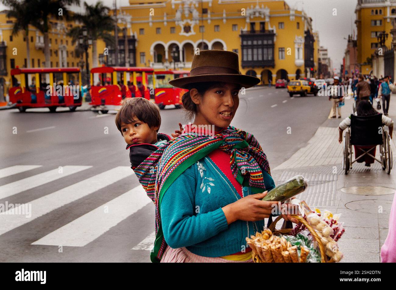 Venditore ambulante di abbigliamento tradizionale andino che vende spuntini - Colonial Yellow Architecture, Centro de Lima Foto Stock