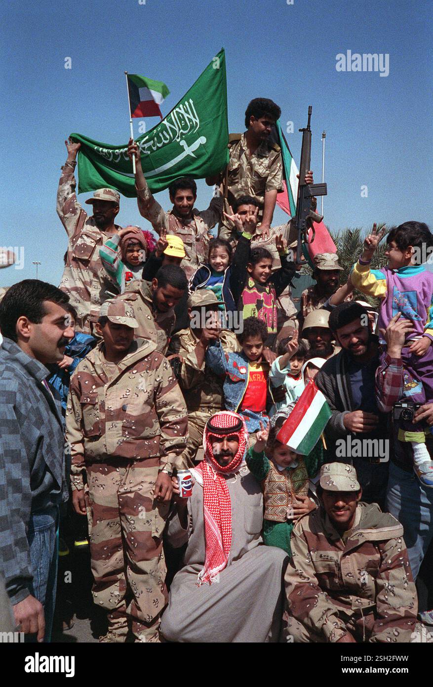 KUWAIT CITY, KUWAIT - 28 febbraio 1991 - civili e forze militari della coalizione ondano bandiere kuwaitiane e saudite a Kuwait City, Kuwait, mentre loro Foto Stock