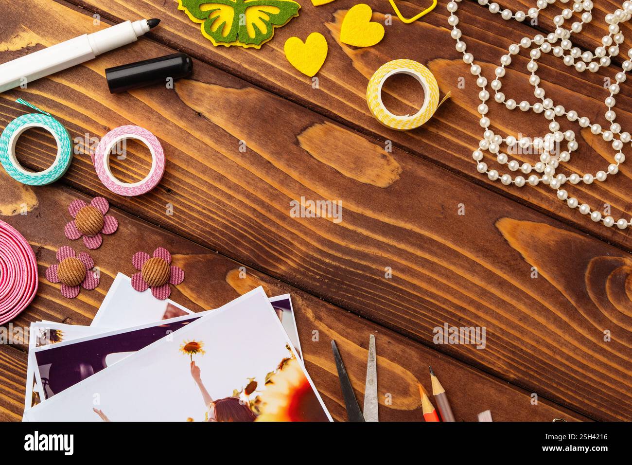 Spazio di lavoro creativo con forniture colorate e fotografie stampate disposte su un tavolo di legno Foto Stock