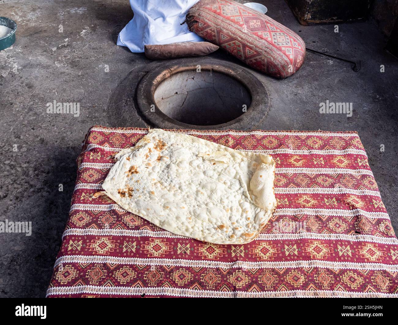 Cucina di piatti nazionali di cucina locale lavash armeno - lavash appena sfornato sul tavolo vicino a tandoor nel cortile della casa del villaggio Foto Stock