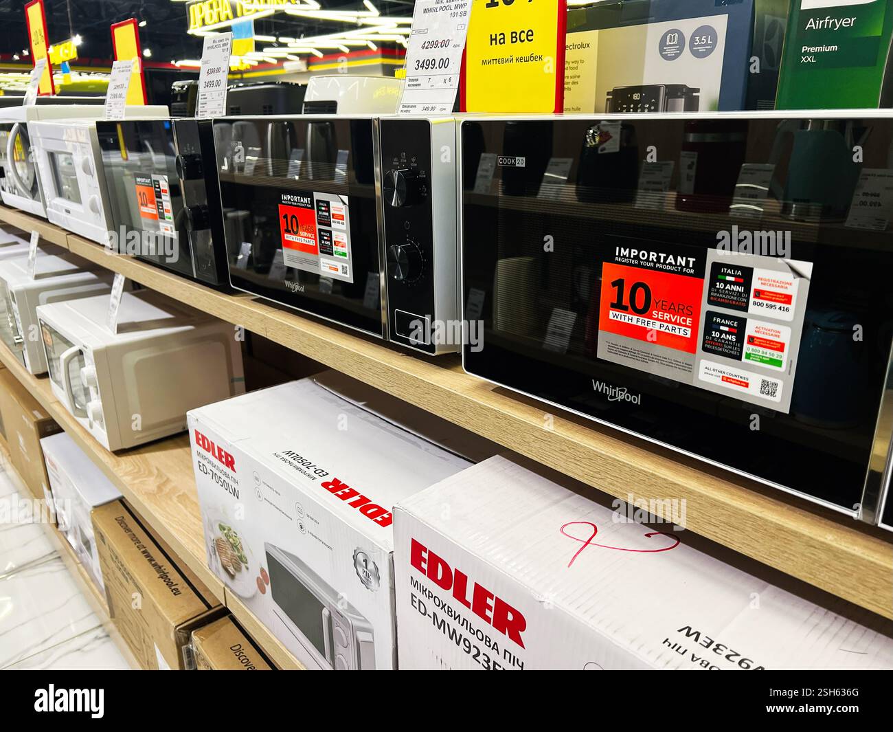 Kiev, Ucraina - 09 febbraio 2025: Forni a microonde presentati in un negozio con cartellini di vendita e informazioni promozionali. Foto Stock