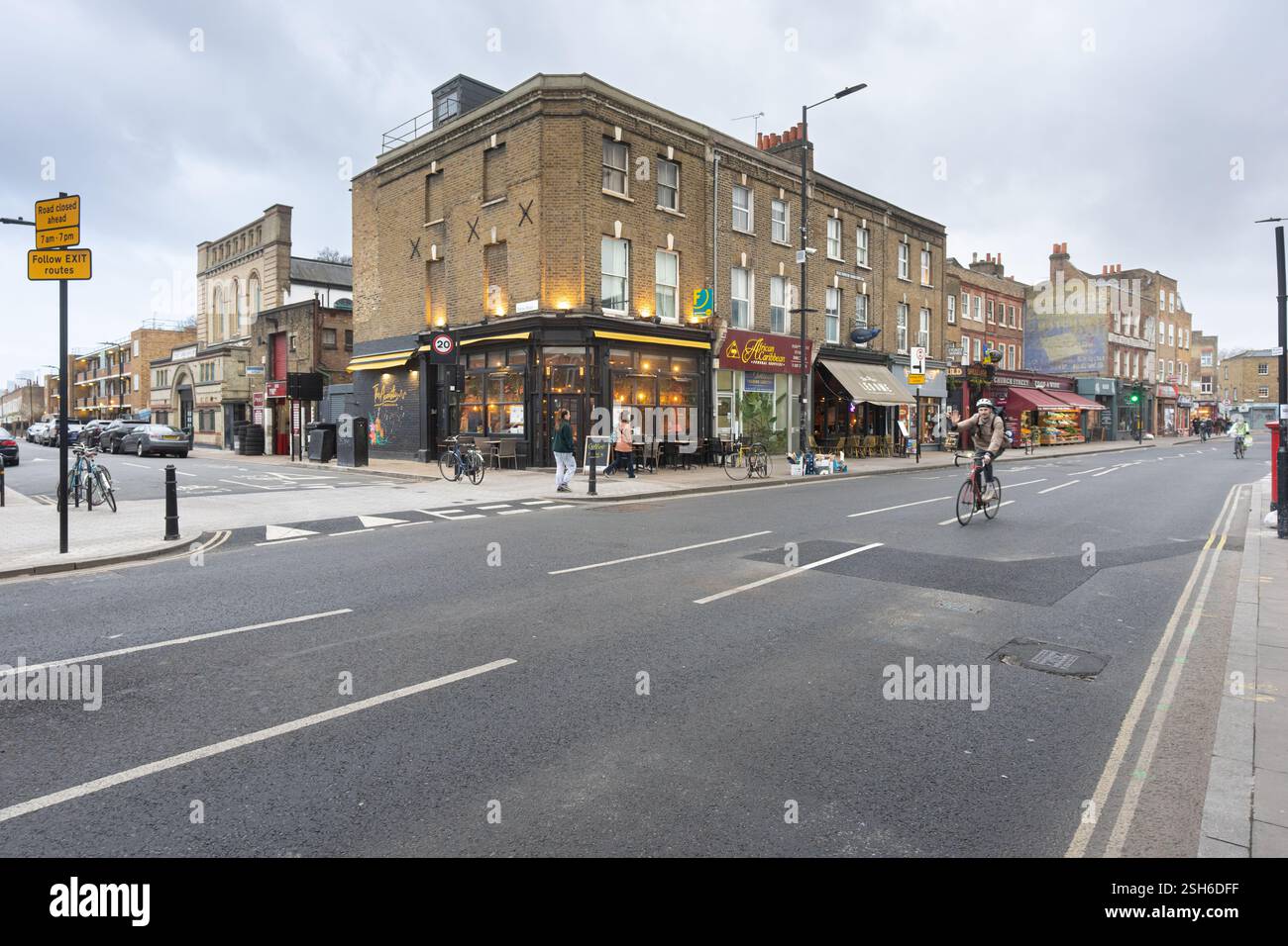 Ciclista su Stoke Newington Church Street, Londra, vicino a un cartello di chiusura della strada. Pedoni e negozi sono visibili. Foto Stock