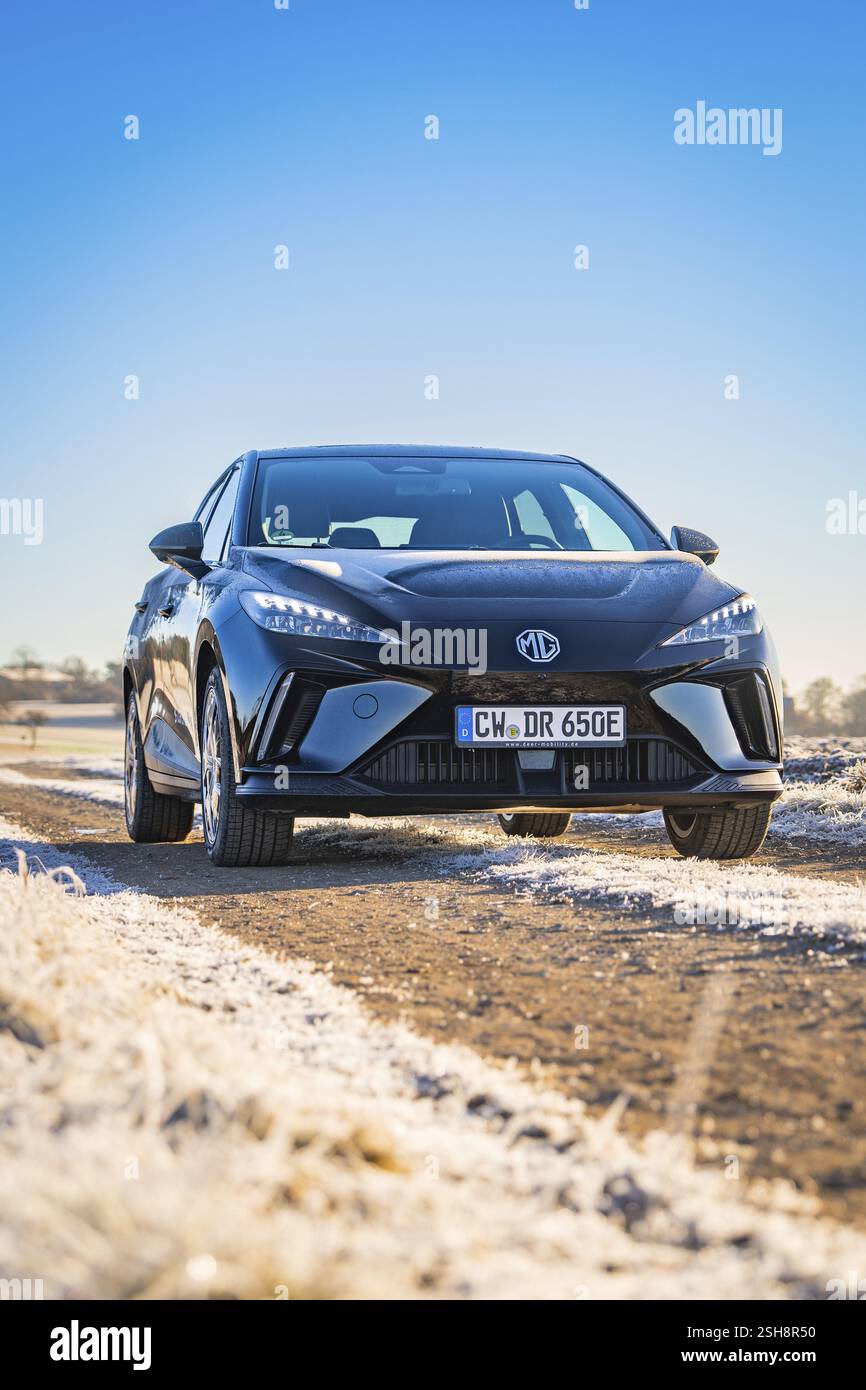 Auto nera che guida su una strada innevata sotto un cielo limpido, veicolo di condivisione di e-car di Deer Mobility, Gechingen, Foresta Nera, Germania, Europa Foto Stock