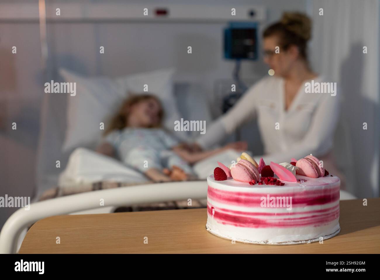 Una scena toccante di una madre e suo figlio all'interno di un ospedale che festeggia con una torta Foto Stock